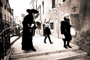 Venice - Little girl staring at man in carnival costume, black and white landscape photo