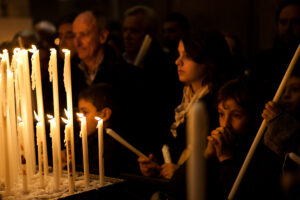 Venice - people in prayer after the offering of the candle inside Church of Salute, color landscape photo