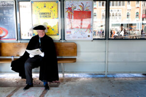 Venice - Venetian resident in carnival costume waiting for waterbus, color landscape photo