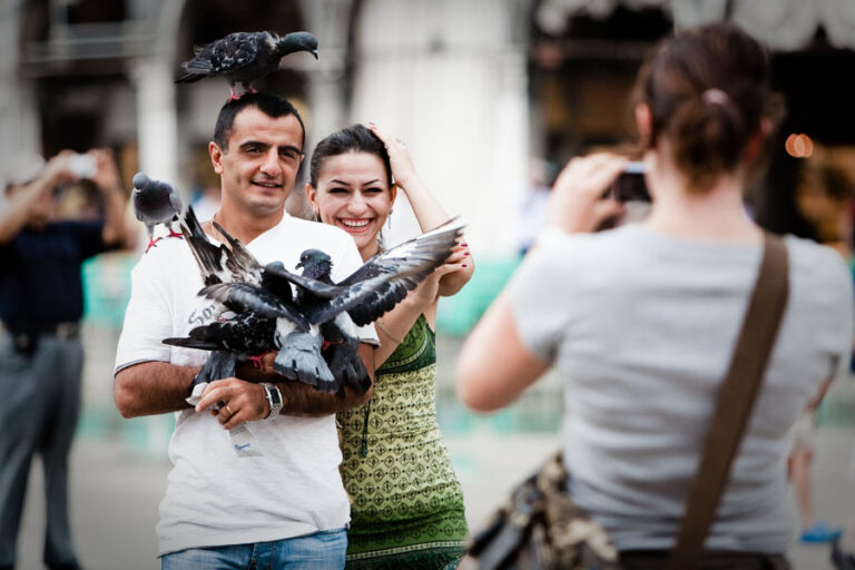 Venice - tourists photographed with pigeons in St. Mark's square, color landscape photo